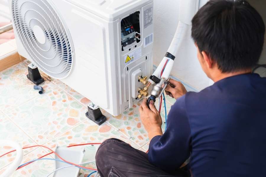 A technician connects copper pipes to the outdoor unit during an AC installation